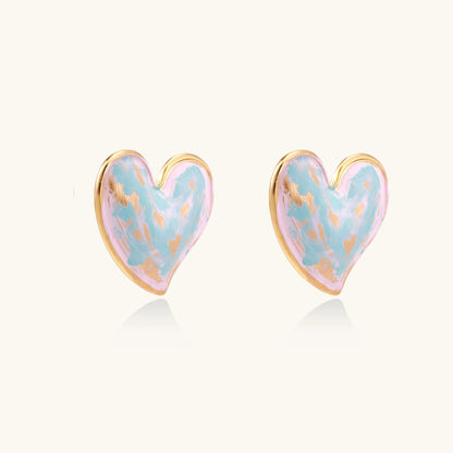Heart-shaped stud earrings with swirled turquoise and pink enamel in gold-plated frames on cream background